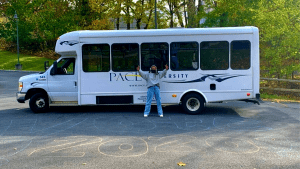 student standing in front of shuttle bus