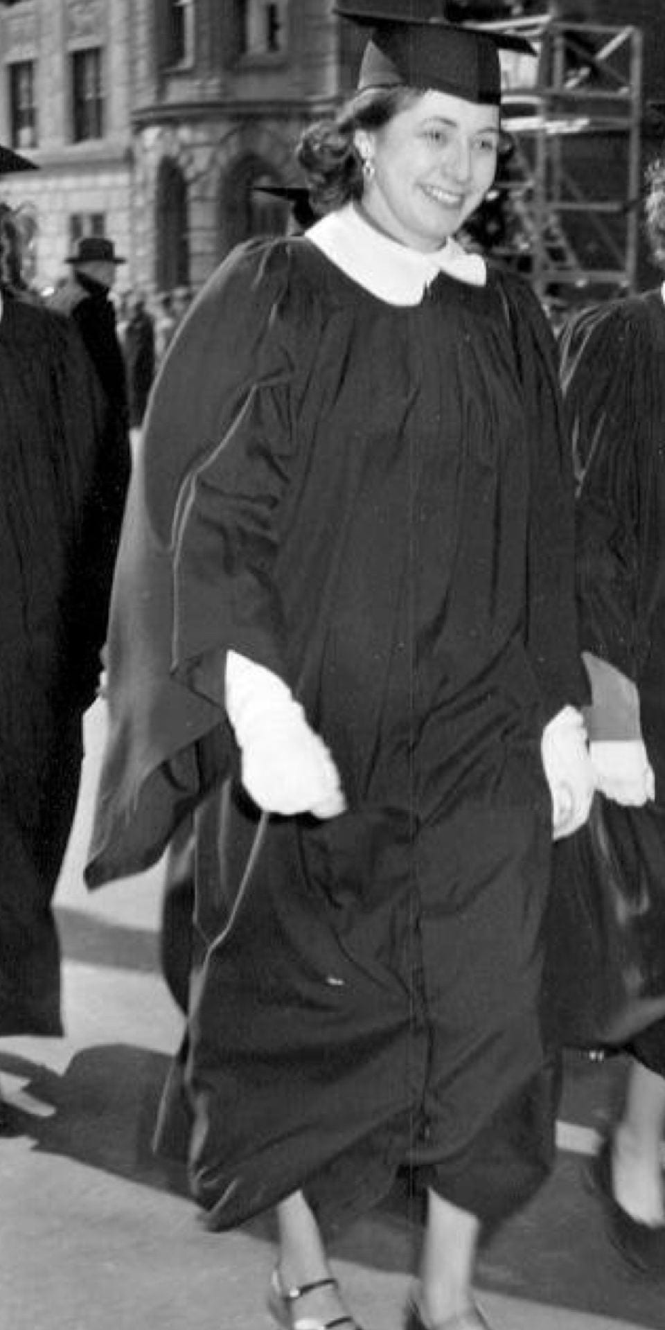 black and white photo of young woman in graduation regalia