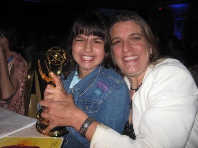 a woman and a young girl holding an Emmy